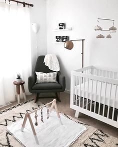 a baby's room with a white crib, black and white rug, wooden rocking chair, and pictures on the wall