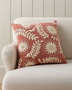 an orange and white pillow sitting on top of a couch next to a wooden wall