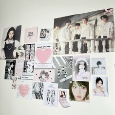 a white wall covered in pictures and magnets next to a pink heart hanging on the wall