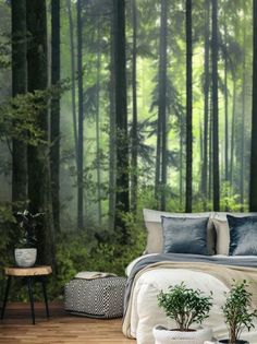 a bed room with a neatly made bed next to a forest wall mural on the wall