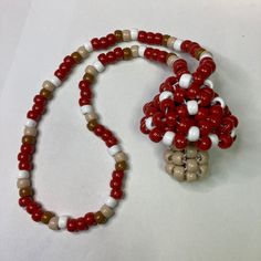 a red and white beaded necklace on a white surface