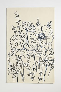 a blue and white drawing of flowers on a linen wall hanging in front of a white wall