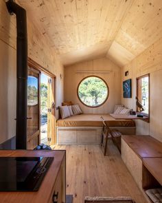 the interior of a tiny cabin with wood floors and round window on the side wall