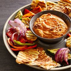 a platter with grilled vegetables and hummus on it, along with pita bread