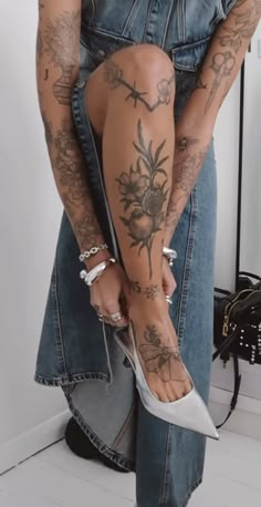 a woman with tattoos on her legs and heels is holding onto the leg of another person