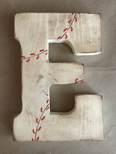 the letter e is made out of wood and has red berries on it, along with a white background