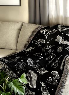 a black and white blanket on a couch next to a potted plant