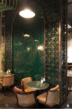 the interior of a restaurant with green walls and wicker chairs around a glass table