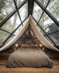 a bed in the middle of a room with lots of windows on top of it