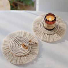 a candle is sitting on top of two coasters that are made out of yarn