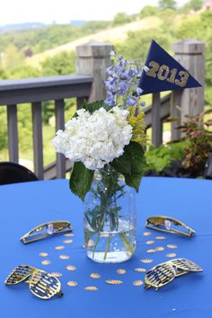 a vase filled with white flowers sitting on top of a blue table covered in confetti