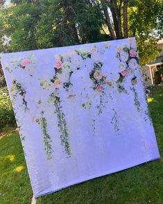 a large white and pink flowered backdrop in the grass