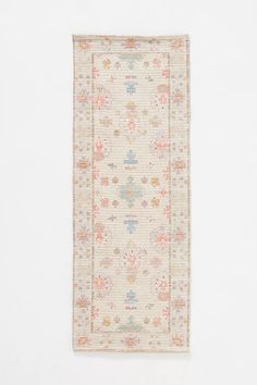 a white rug with floral designs on the front and back, against a white wall