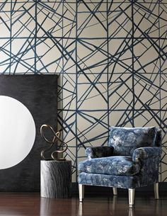 a blue chair sitting in front of a black and white wall with an abstract design on it