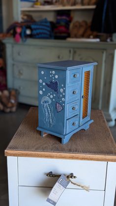 a small blue cabinet sitting on top of a white dresser