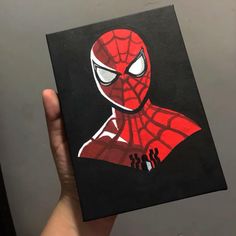 a hand holding up a drawing of a spider - man in red and black colors