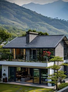 a large house sitting in the middle of a lush green hillside with mountains in the background