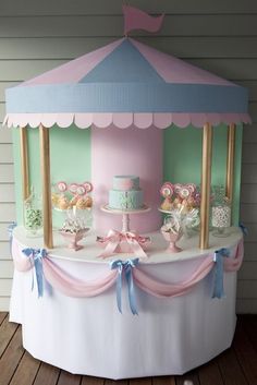 a pink and blue carousel cake stand with cupcakes on it's sides