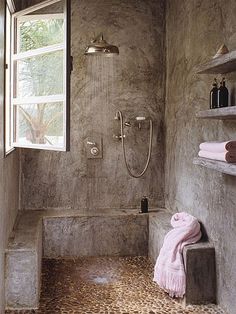 a bath room with a toilet a shower and some shelves on the wall next to a window