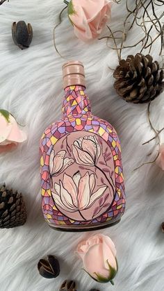 the bottle is decorated with pink flowers and pineconi on a white furnishing