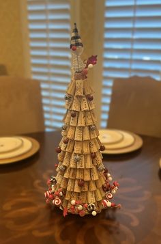 a christmas tree made out of wine corks on a dining room table with place settings