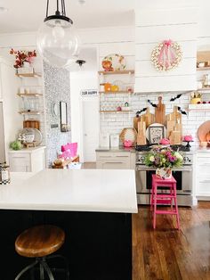 a kitchen with white walls and wooden floors has an island in front of the stove