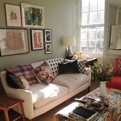 a living room filled with lots of furniture and pictures on the wall above it's windows