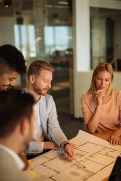 three people sitting at a table with architectural plans in front of them - stock photo - images