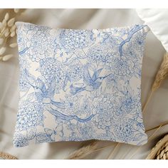 a blue and white pillow sitting on top of a bed next to some dried flowers