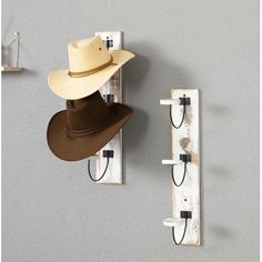 two hats are hanging from hooks on the wall