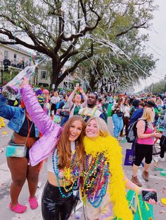 two women standing next to each other in front of a group of people at a parade