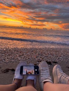 two people are sitting on the beach with their feet propped up in front of them