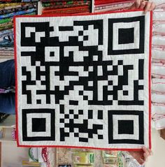 a person holding up a black and white qr code quilt