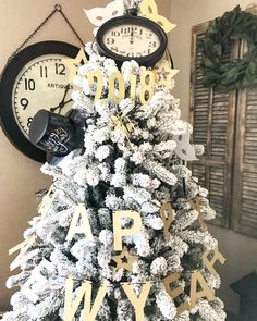 a white christmas tree with gold letters and clocks on the top, in front of a wall clock