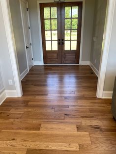 an empty entryway with two doors and hard wood flooring on the other side