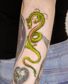 a woman's arm with a green snake tattoo on it and a heart in the background