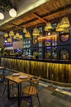 the interior of a restaurant with wooden tables and chairs, hanging lights, and gold fixtures