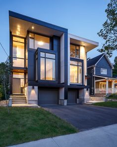 a modern house with large windows and stairs leading to the front door at night time