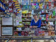 a woman standing in front of a store filled with lots of food and snacks on display