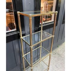 a gold metal shelf with glass shelves in front of a store