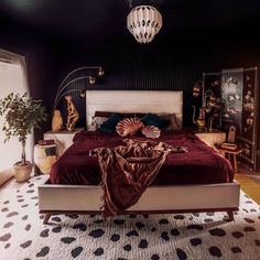 a bedroom with black walls, white bedding and a red comforter on top of the bed