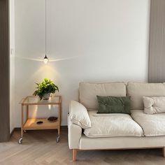 a white couch sitting next to a table with a potted plant on top of it