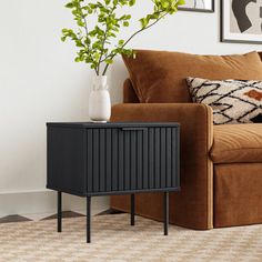 a brown couch sitting next to a wooden table with a vase on top of it