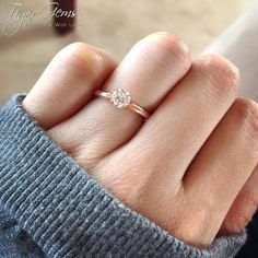 a woman's hand with a diamond ring on top of her finger, showing the middle