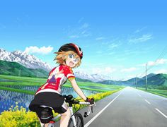 a woman riding a bike down a road next to yellow flowers and mountains in the background