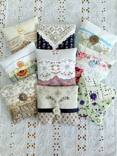 many different types of decorative pillows on a white tablecloth with lacy doily behind them