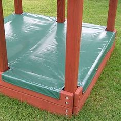 a wooden structure with green tarp on the top and bottom part, in grassy area