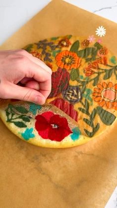 a person is making an art project with colored paper and scissors on a piece of brown paper