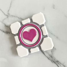 a white and pink object with a heart in the center on a marble counter top