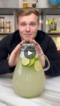 a man sitting at a table with a pitcher filled with lemonade and limes